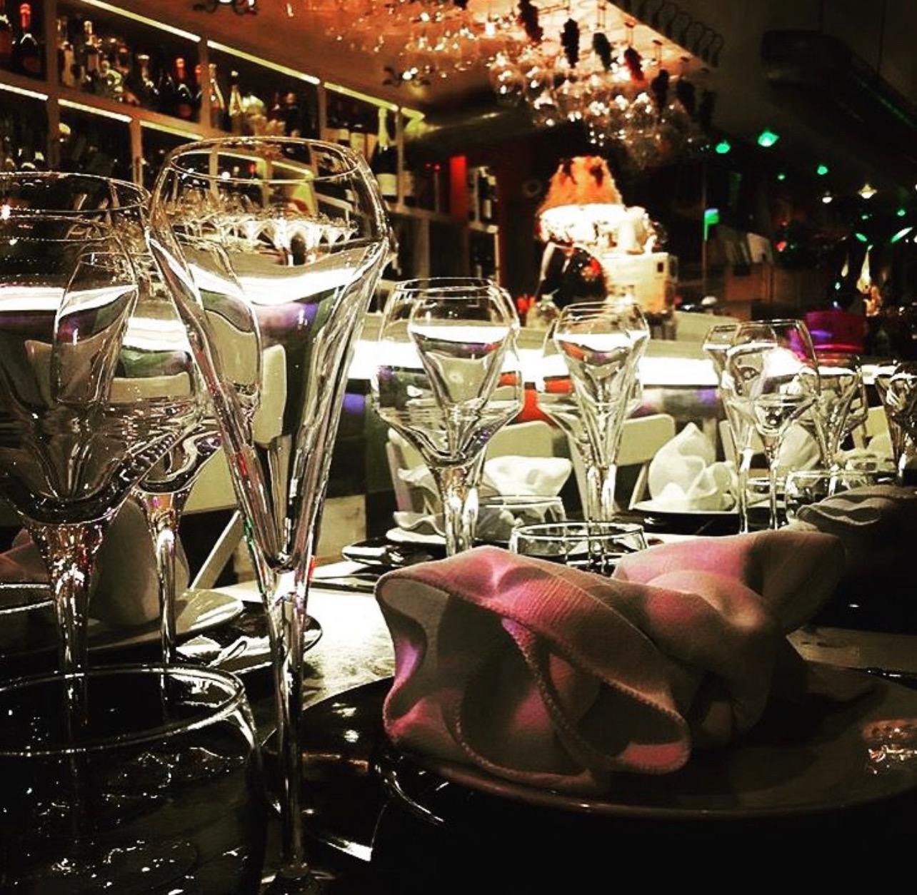 Glasses and folded napkins on a set table in the softly lit restaurant