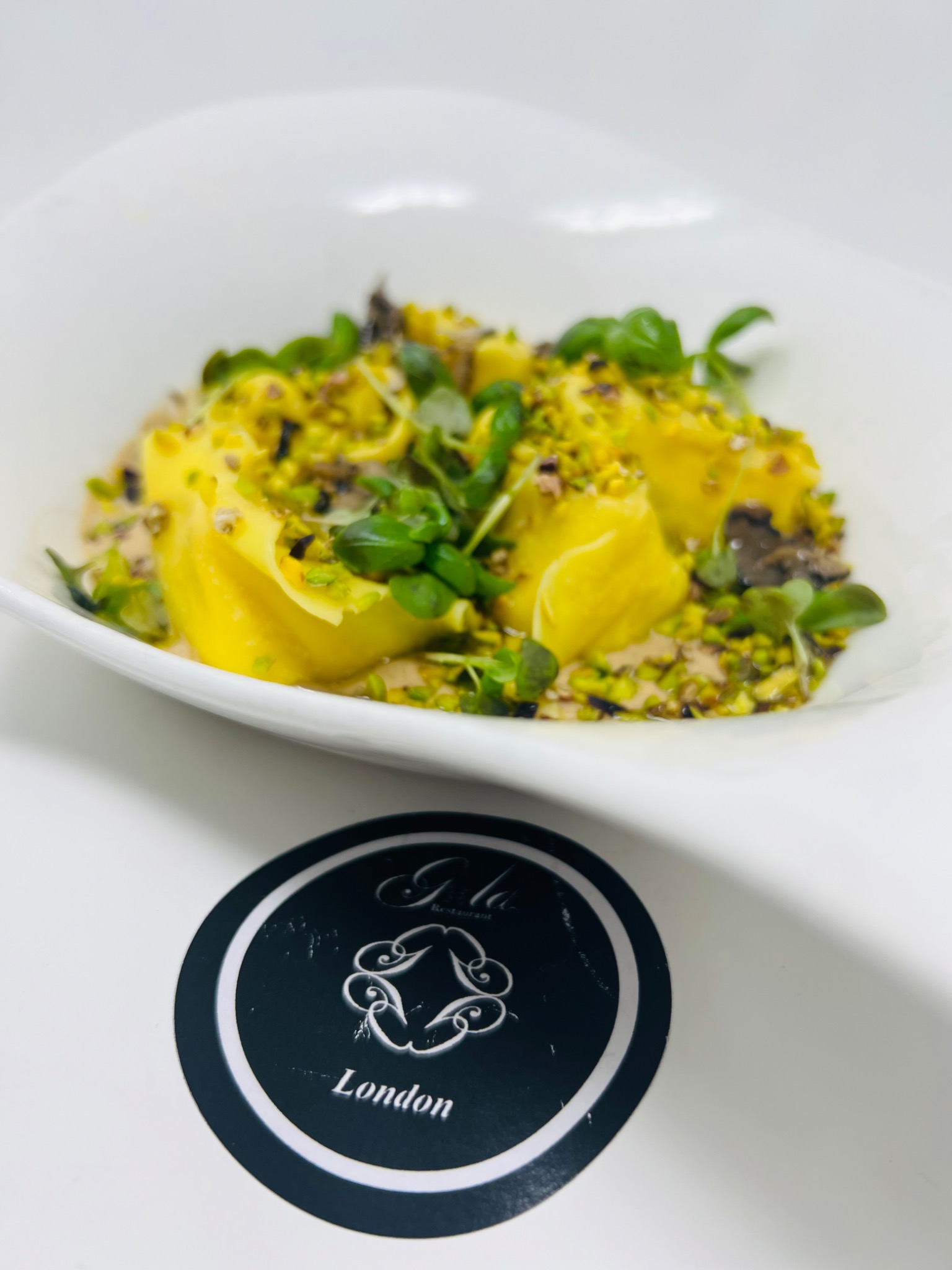 Ravioli with pecorino cheese, honey and pistachio, served in a white bowl