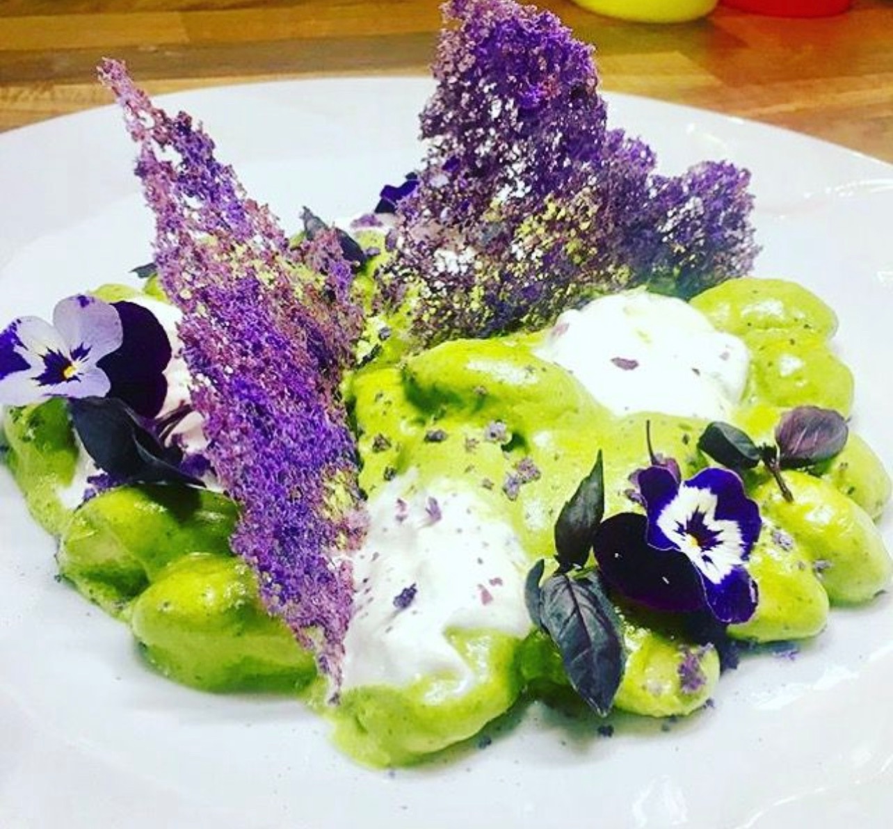 Gnocchi in pesto sauce, with violet crisps and flowers