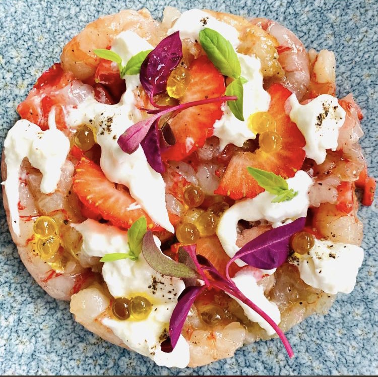 A colourful round composition with strawberries, white dollops, leaves and golden pearls